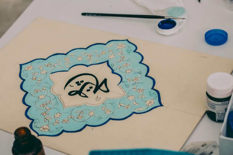 Intricate calligraphy art with blue floral patterns on paper, crafted with precision.