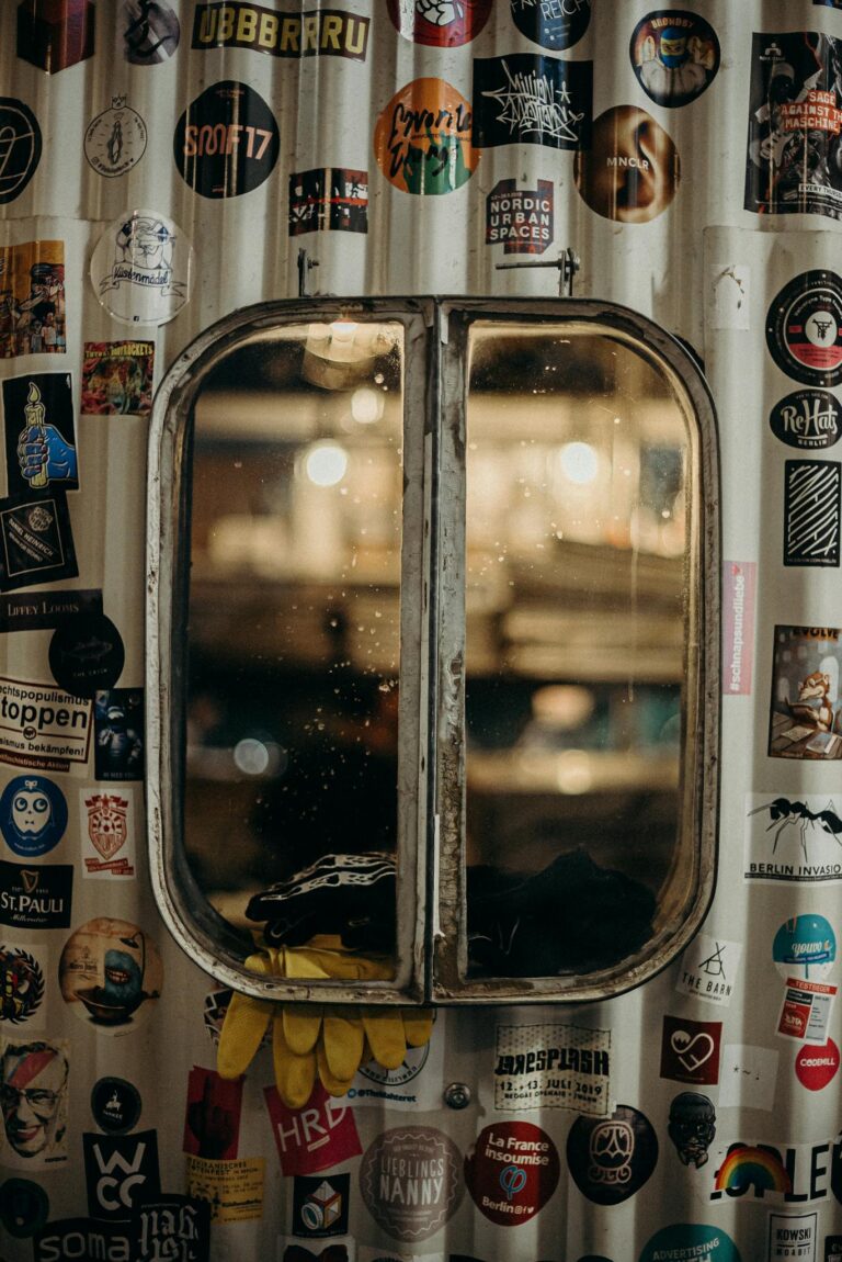 Rustic window adorned with eclectic stickers and gloves, creating an urban charm.